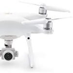 A white quadcopter drone with a camera and a separate remote control with a display screen.