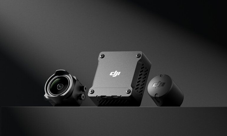 DJI camera components on a dark surface, including a camera lens, square module, and cylindrical cap.