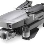 A compact, folded drone with a camera on its front, featuring a gray metallic finish and black propellers.