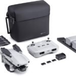 Drone kit with a foldable drone, remote controller, carrying case, two batteries, charger, extra propellers, and memory cards, all arranged on a white surface.