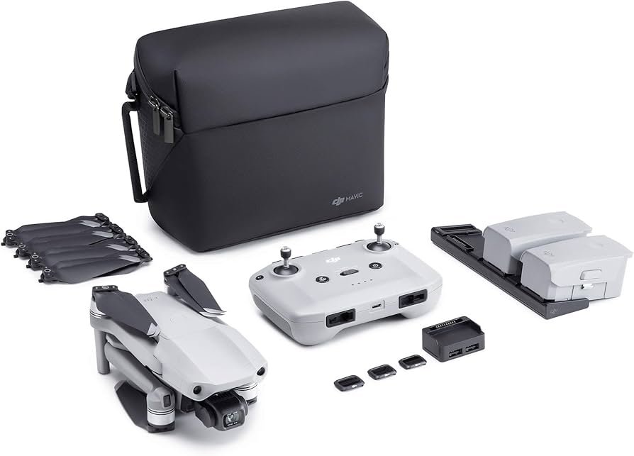 Drone kit with a foldable drone, remote controller, carrying case, two batteries, charger, extra propellers, and memory cards, all arranged on a white surface.