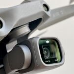 Close-up of a drone camera labeled with "1 INCH" and "20 MP" on a DJI device, showing its lens and part of the drone's framework.