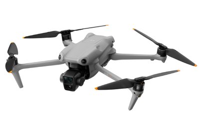 A gray quadcopter drone in flight with four propellers and a camera mounted at the front.