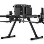 A black quadcopter drone with four propellers and landing gear against a white background.