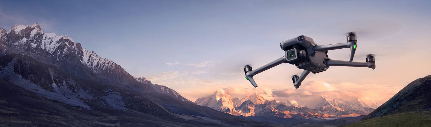 A drone in flight above a mountainous landscape during sunset.