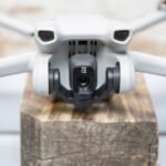 Close-up of a gray drone with a camera, labeled "Mini 3," resting on a wooden surface.