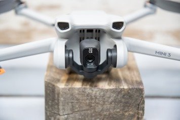 Close-up of a gray drone with a camera, labeled "Mini 3," resting on a wooden surface.