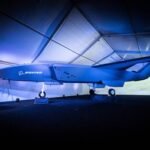 A modern unmanned aerial vehicle displayed in a well-lit indoor tent with a blue and white color scheme.