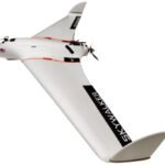 White Skywalker UAV with a sleek, fixed-wing design and propeller, featuring an American flag decal and the word "SKYWALKER" on the wing.