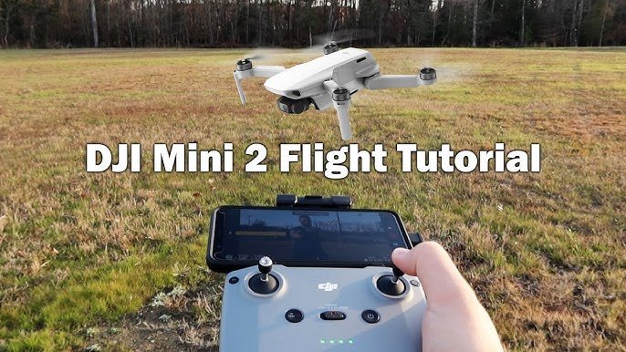 Drone flying over a grassy field with a person holding a remote controller and smartphone. Text reads "DJI Mini 2 Flight Tutorial.