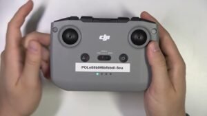 Hands holding a DJI drone controller with a visible serial number sticker on a white background.