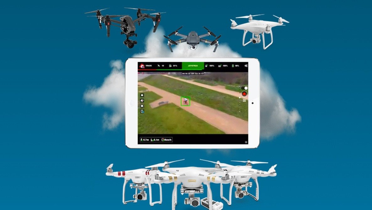 A tablet displaying a drone view is surrounded by various drones against a cloudy blue sky background.