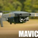 A Mavic Pro drone hovering outdoors with spinning rotors. "Mavic Pro" and "4K" text are visible on the image. Trees and grass are in the background.