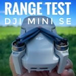 Close-up of a DJI Mini SE drone held against a backdrop of a green field and blue sky. Text above reads "RANGE TEST DJI MINI SE.