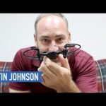 A person holding a small drone with a blue label displaying the name "Martin Johnson.