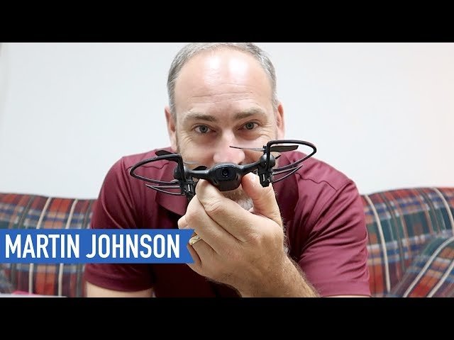 A person holding a small drone with a blue label displaying the name "Martin Johnson.