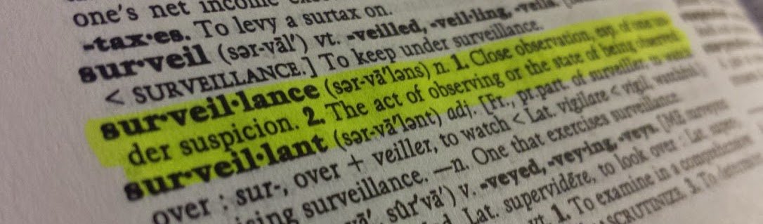 Close-up view of a dictionary page with the word "surveillance" and its definition highlighted in yellow. The text describes the act of observing someone under suspicion.