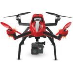 Red and black quadcopter drone with camera attached underneath, seen from the front on a white background.